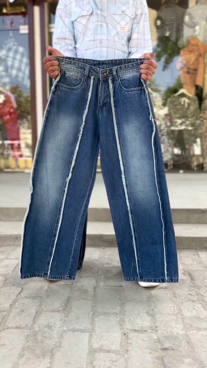 These blue denim jeans feature distinctive white panel detailing down the front of the legs and are often styled as upcycled or Y2K-inspired fashion.